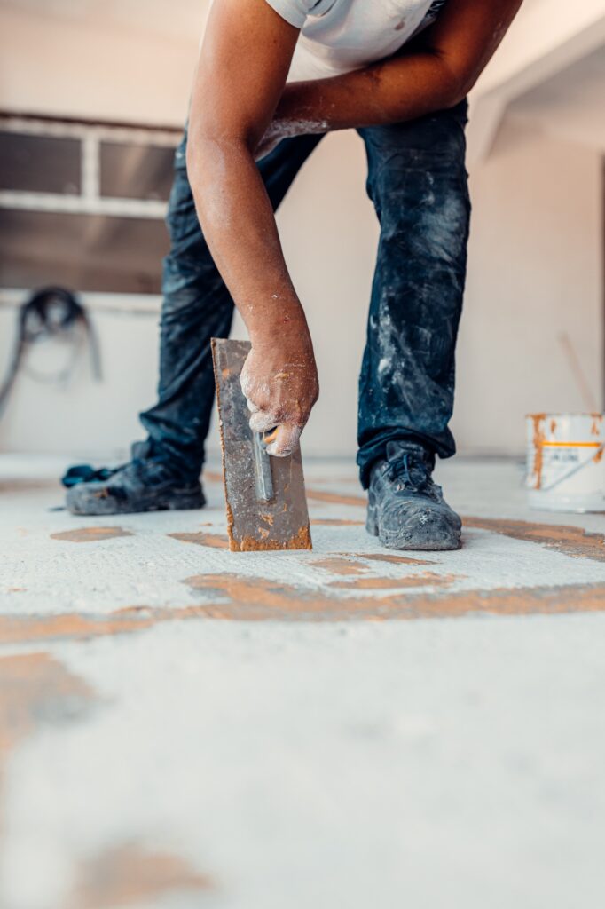 Professional worker repairs cracks in the floor for the epoxy resin layer